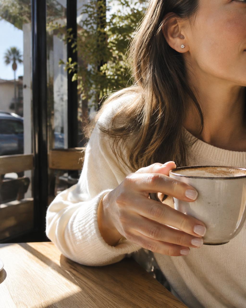 Woman holding coffee wearing diamond studs